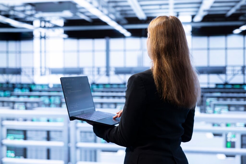 Technician using laptop in data center to do disaster recovery planning