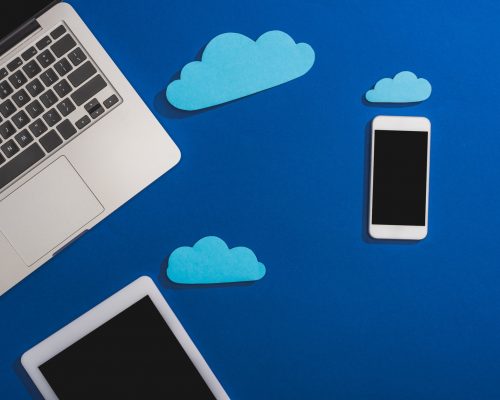 top view of empty paper clouds near laptop, smartphone and digital tablet with blank screen isolated
